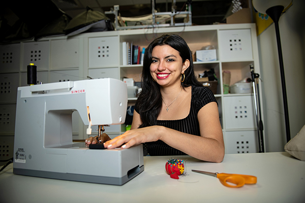  A brunette female in a black shirt uses a sewing machine.