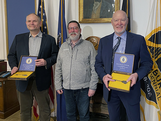  A portrait of Andrew Moore and Red Whittaker with Bill Peduto. Each man is holding a ceremonial key to the city.