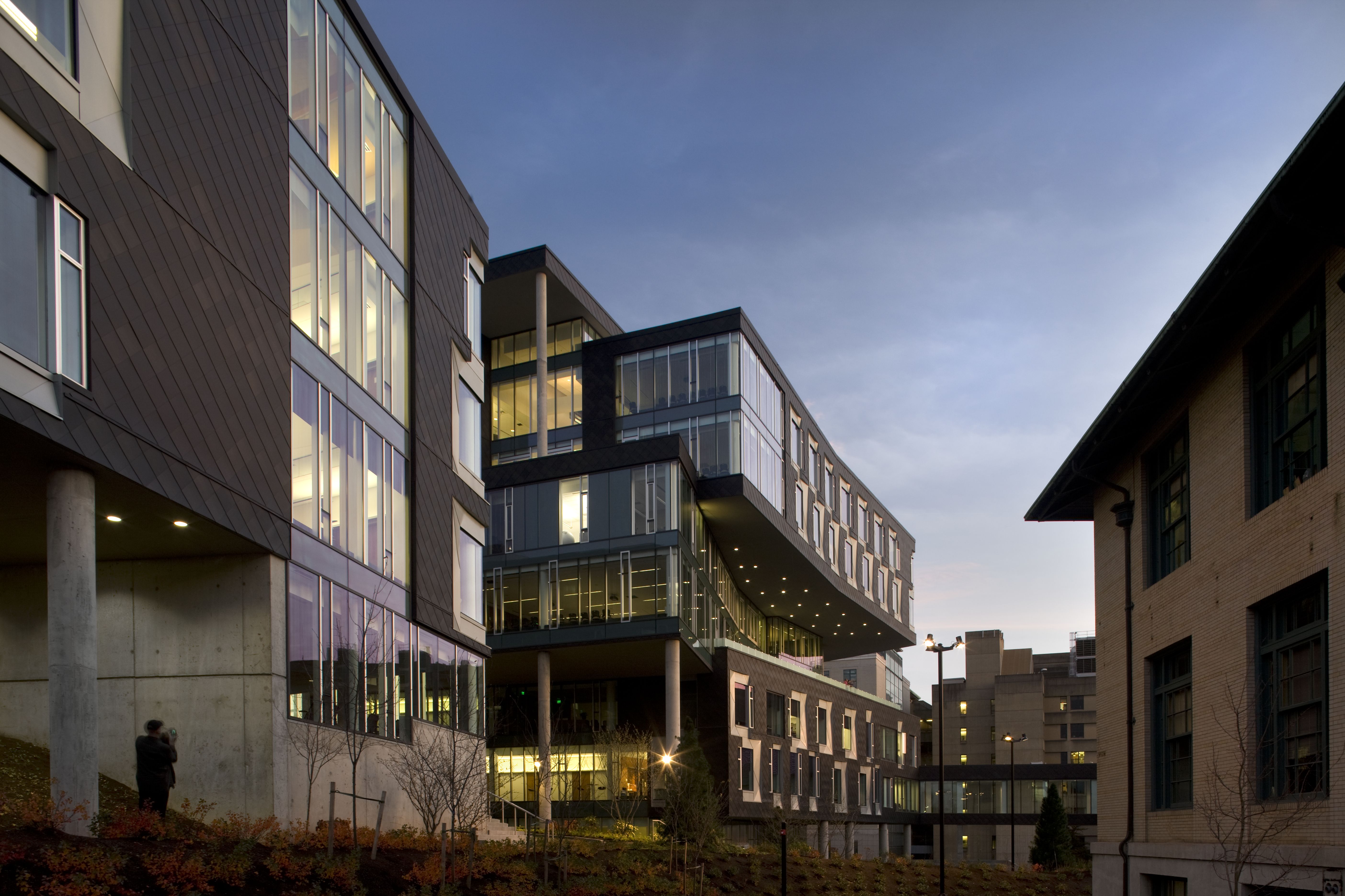 An exterior shot of a multi-storey building set close to a road. The building is a combination of glass and buff brick and some small trees are planted in front of it.